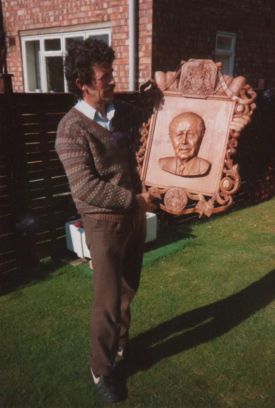 A younger Jose holds the completed carving. - harold macmillan carving wooden plaque